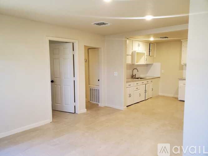 A kitchen area with white cabinets and a white door.