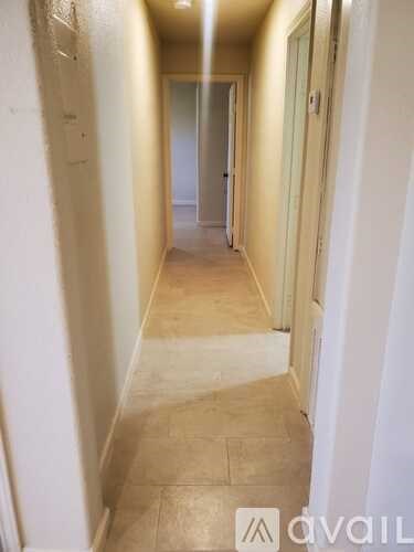 A long hallway with tiled floors and white walls.