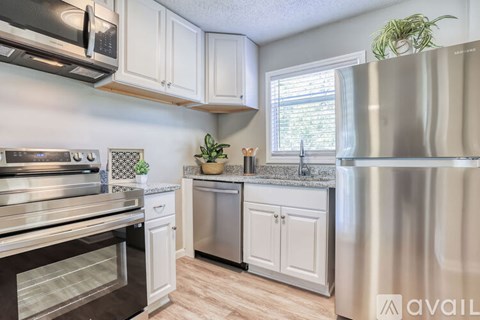 A kitchen with white cabinets and a stainless steel refrigerator.