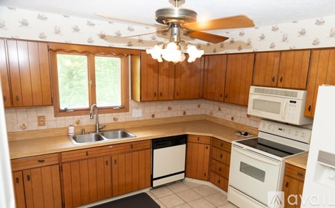 A kitchen with wooden cabinets and a ceiling fan.