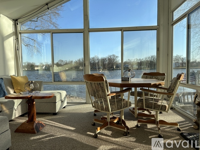 A sunny day at the lake with a table and chairs set up on a balcony.