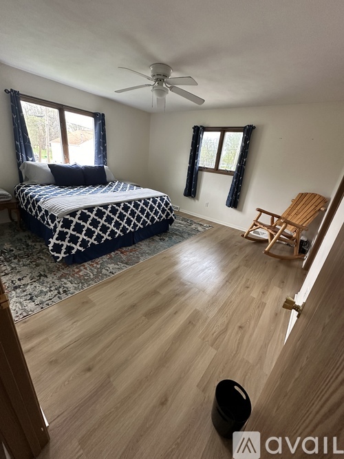 A bedroom with a bed, chair, and window.