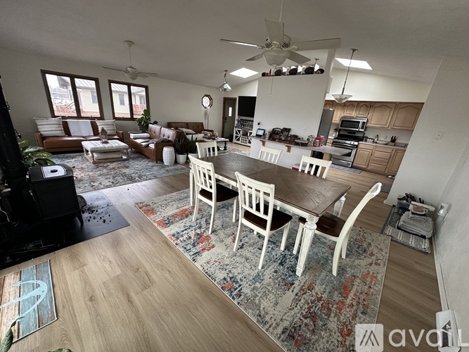 A well-lit, spacious living room with a dining area and kitchen in the background.