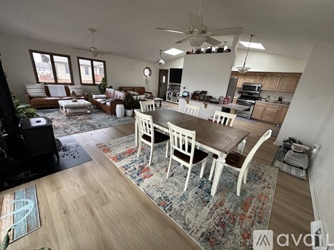 A well-lit, spacious living room with a dining area and kitchen in the background.