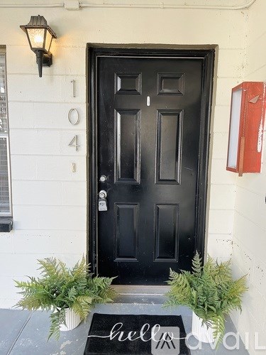 A black door with a mat that says "hello" in front of it.
