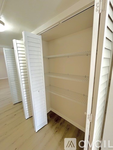 A white closet with shelves and a sliding door.