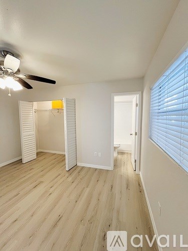 A room with a ceiling fan and wooden flooring.