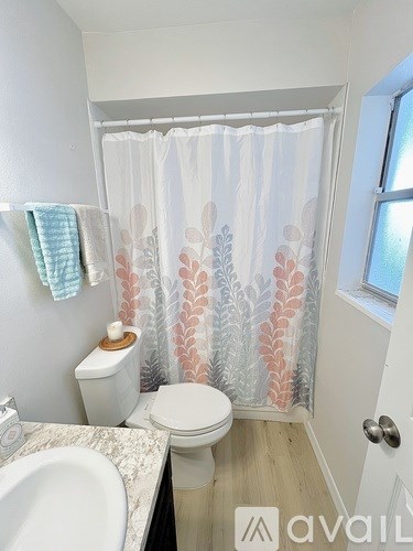 A bathroom with a toilet, sink, and shower curtain.