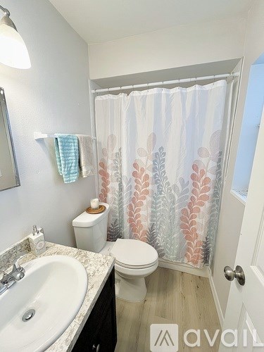 A bathroom with a toilet, sink, and shower curtain.