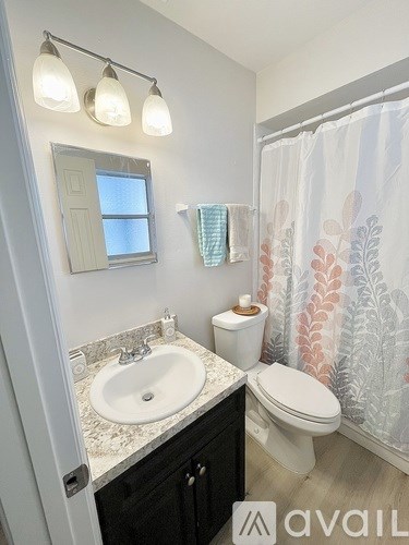A bathroom with a sink, toilet, and a window.