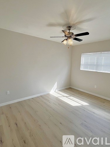 A room with a ceiling fan and wooden flooring.