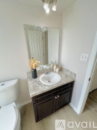 A bathroom with a toilet, sink, and mirror.