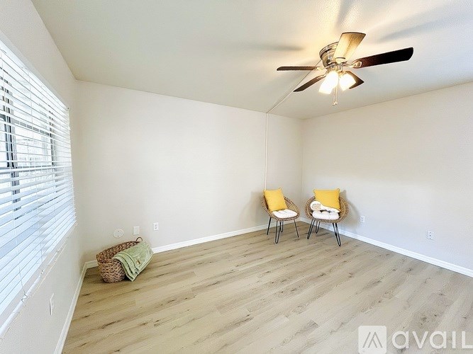 A room with a ceiling fan and two chairs.