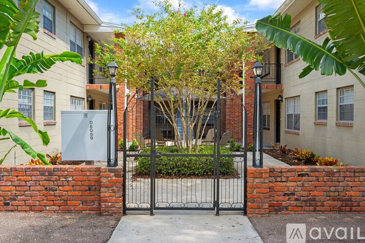A brick wall with a gate and a tree in front of a building.