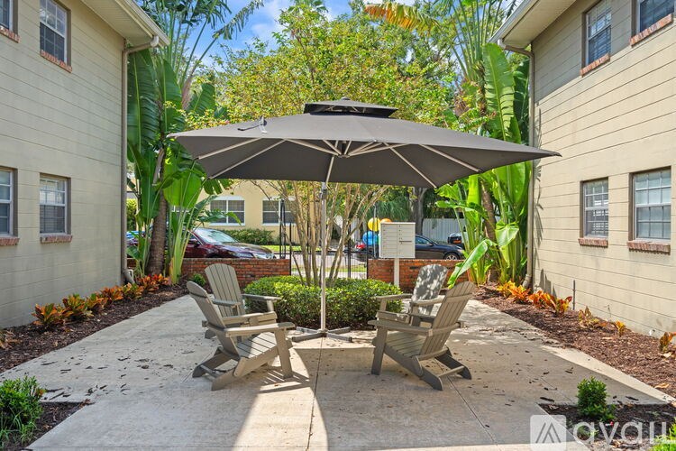 Two chairs are placed under a large umbrella on a patio.