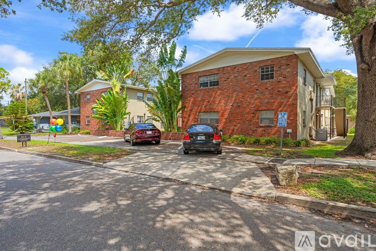 A red brick house with a tree in front of it.