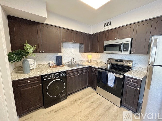 A kitchen with dark brown cabinets and a white countertop.