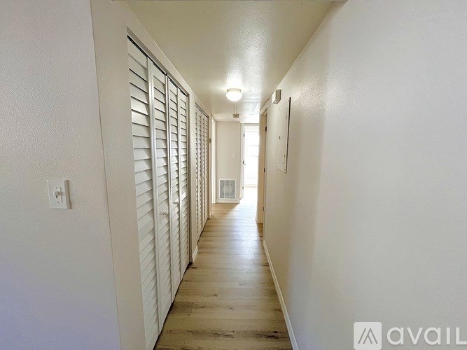 A long hallway with white walls and wooden floors.