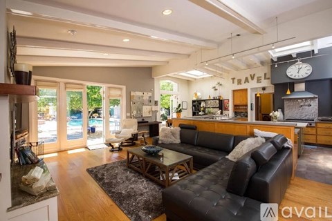 A living room with a black leather couch and a coffee table.