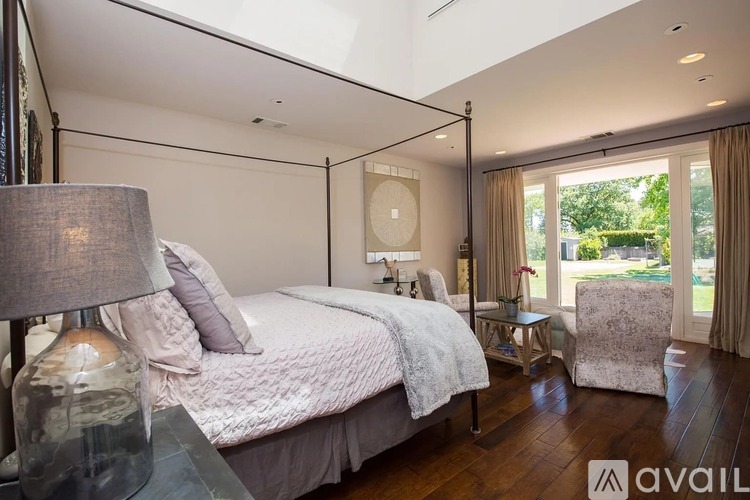 A bedroom with a large bed and a chair.