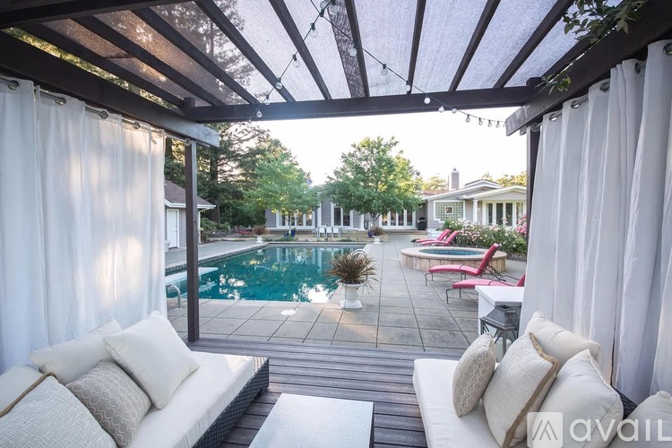 A patio with a white couch and a pool in the background.