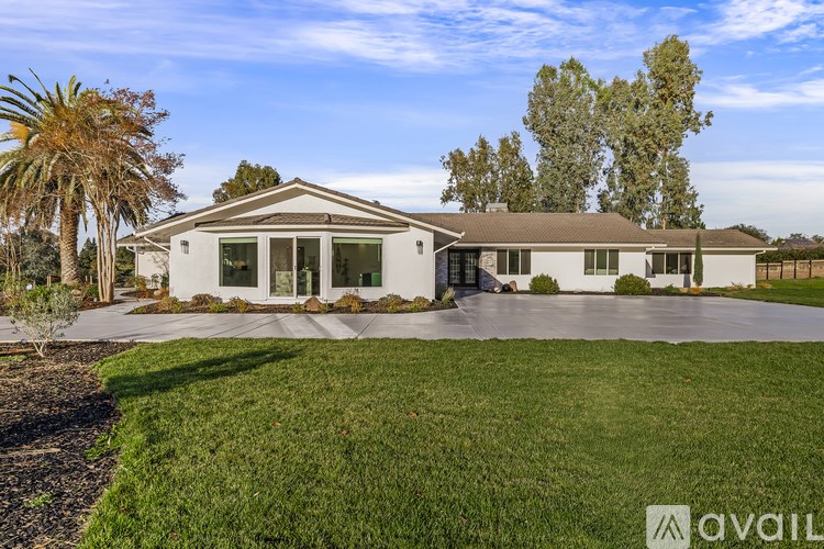 A house with a well-maintained lawn and trees in the background.