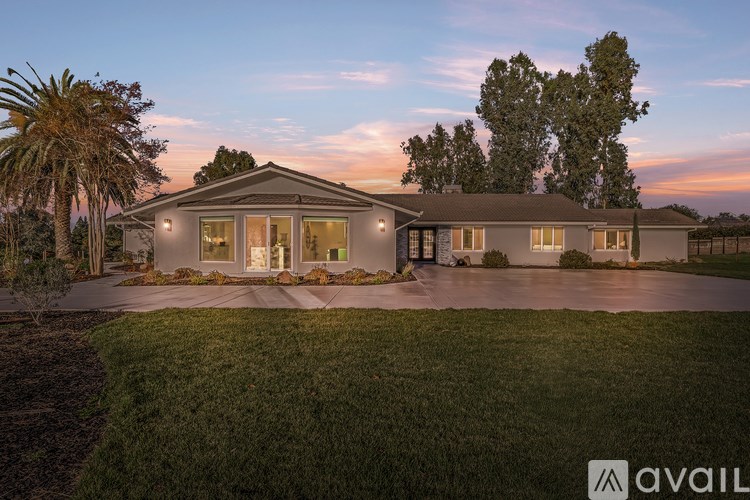 A house with a well-manicured lawn and trees in the background is available for purchase.