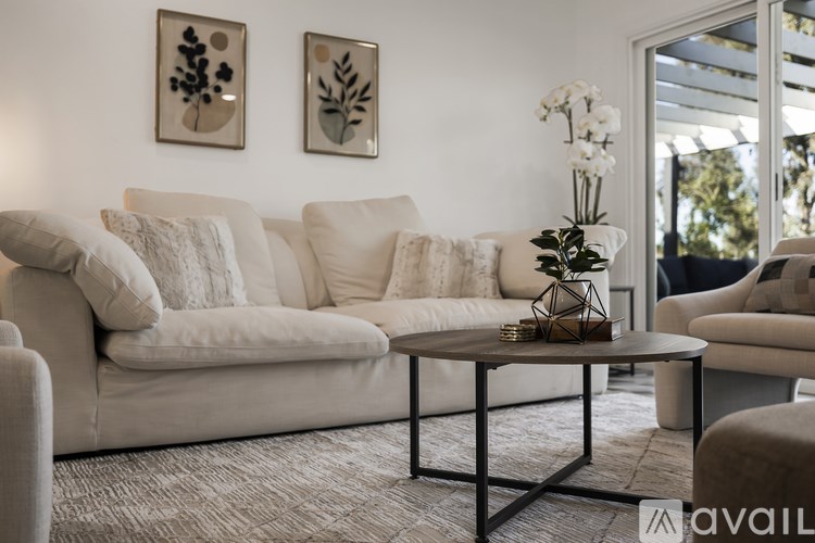 A living room with a white sofa, a coffee table, and two framed pictures on the wall.