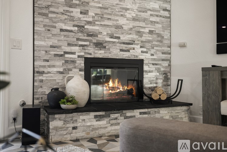 A modern fireplace with a stone wall and a fire burning inside.