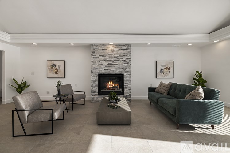 A living room with a stone fireplace and a green couch.