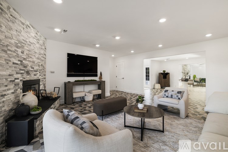 A modern living room with a stone fireplace and a variety of seating options.