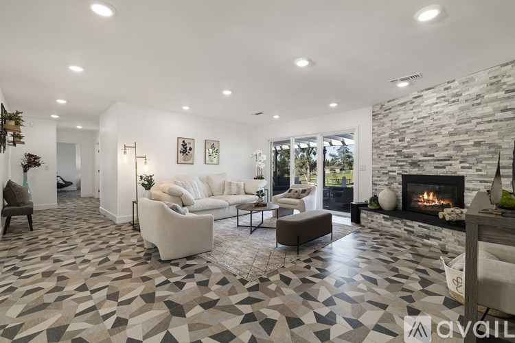 A living room with a stone fireplace and a tiled floor.