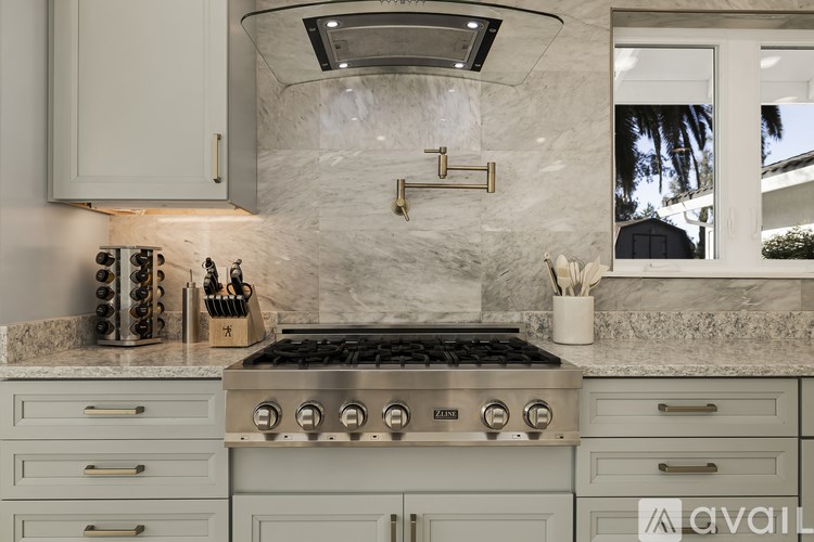 A kitchen with a stove top oven and a marble backsplash.