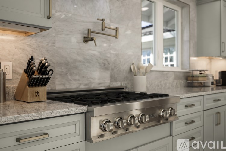 A kitchen with a stove top oven and a knife block on the counter.