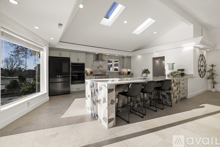 A modern kitchen with a large island and black chairs.