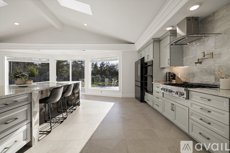 A modern kitchen with a large island and a view of trees outside the window.