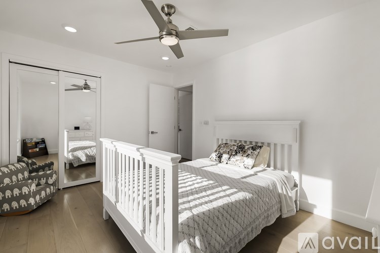 A white bedroom with a large bed and a ceiling fan.