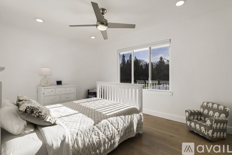 A bedroom with a large bed, a ceiling fan, and a chair.