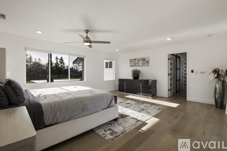A modern bedroom with a large bed and a ceiling fan.