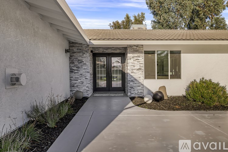 A modern house with a stone wall and a glass door.