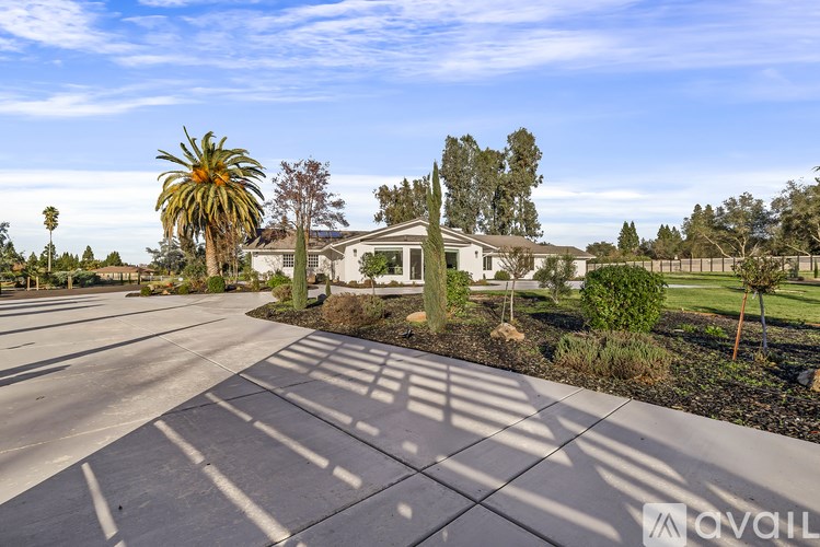 A house with a driveway and palm trees in the background.