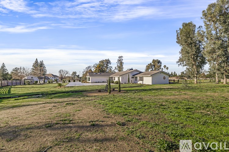 A field with a house and trees in the background.