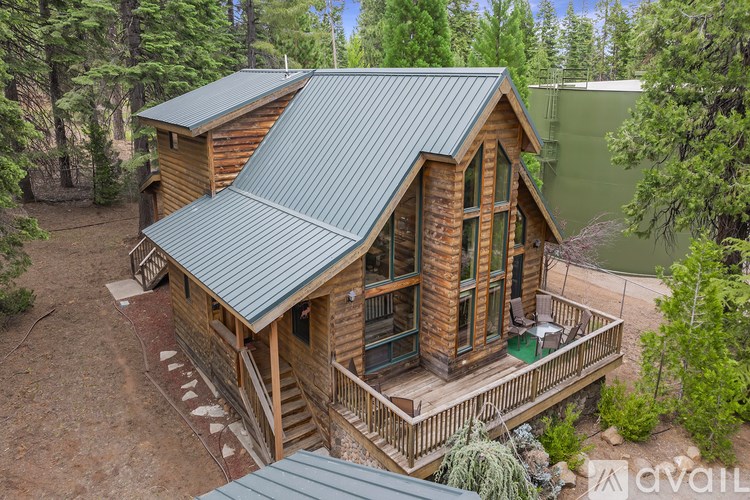 A wooden cabin with a green roof is surrounded by trees.