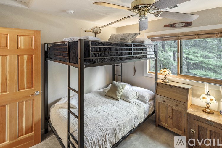 A bedroom with a bunk bed and a window overlooking a forest.