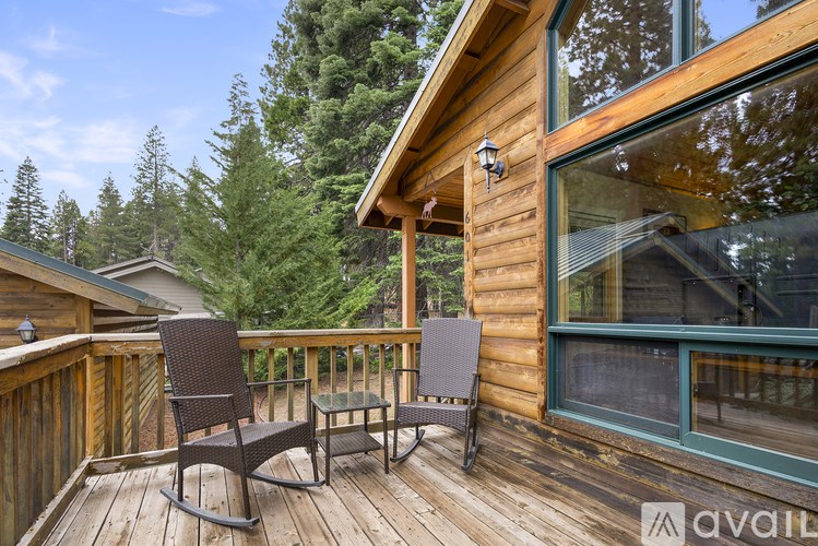 A wooden deck with a table and chairs overlooking a forest.