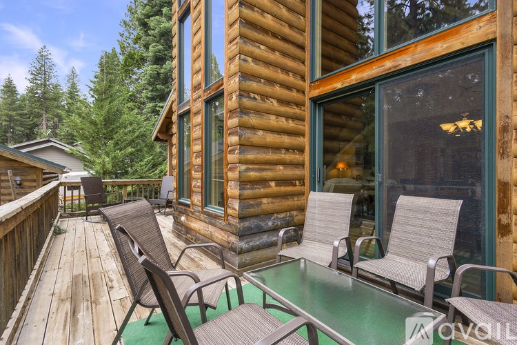A wooden deck with chairs and a table in front of a log cabin.