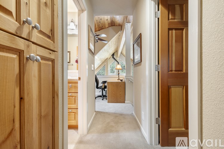 A hallway with a wooden door on the left and a carpeted floor.