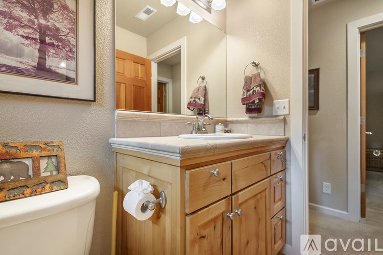 A bathroom with a wooden vanity and a framed picture of a tree on the wall.