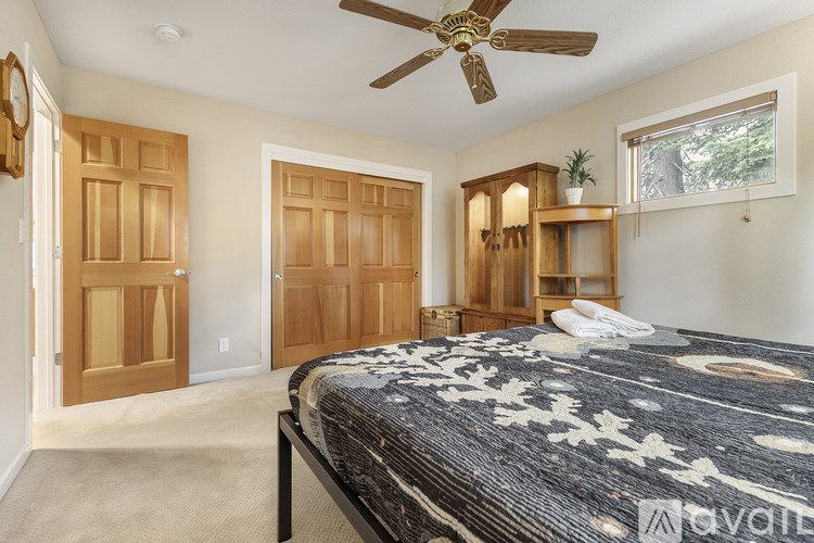 A bedroom with a bed, a ceiling fan, and wooden doors.
