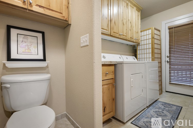 A bathroom with a toilet, a fridge, and a cabinet.